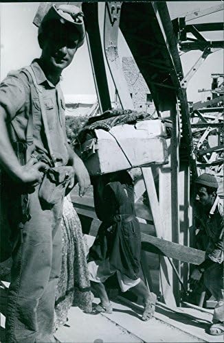 Гроздобер фотографија на офицер гледајќи луѓе кои носат кутии.