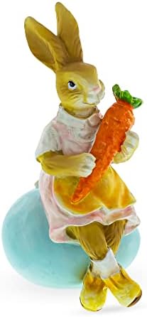 Најдобра мајка зајаче која држи морков и седејќи на фигурата на велигденската јајце